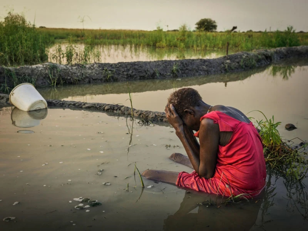 The end of a long day for the exhausted Nyakoang Mayieh, 70, trying to get the water out with a bucket from an already overflooded area. (From 